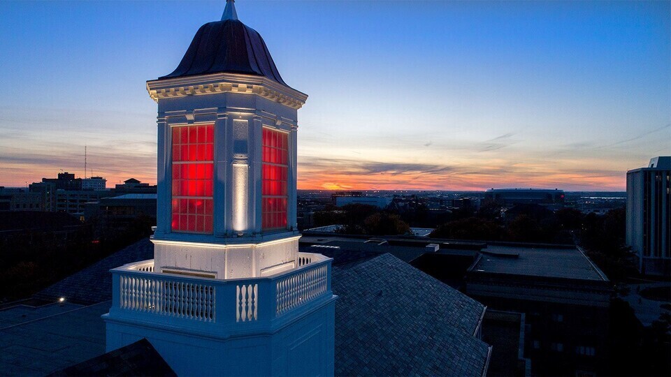 Love Library cupola lit up red at dusk